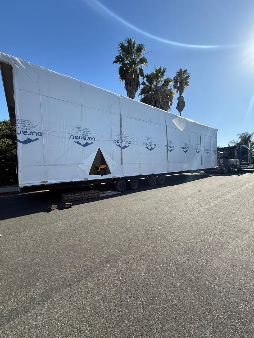 A wrapped manufactured home section arriving on the street.