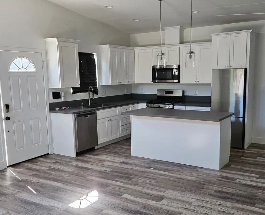 The finished kitchen at 4003 Paula Street: white cabinets, a grey-topped island and wood-look floors.